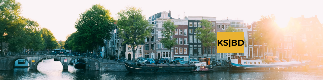 Amsterdamse gracht met brug en boten in warm avondlicht